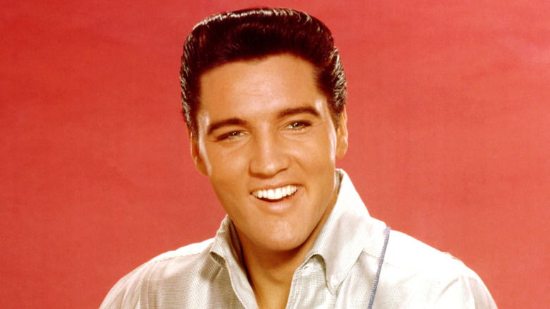Elvis Presley strums an acoustic guitar while posing for a portrait in September 1962