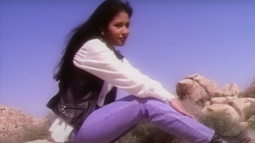 Selena Quintanilla seated on a rock