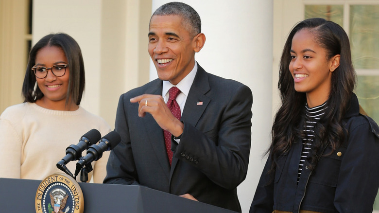 Former President Barack Obama speaking while his daughters look on