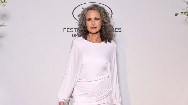 Andie MacDowell wearing a white gown on the red carpet.