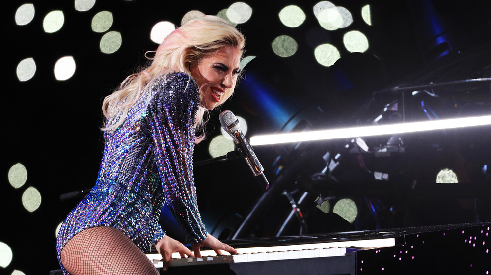 Lady Gaga lifts her leg on top of her piano and sings into the microphone at the 2017 Super Bowl halftime show