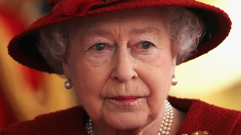 Queen Elizabeth II with serious expression and red hat