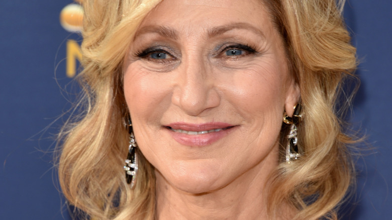 Edie Falco poses with blond hair styled in loose curls. 