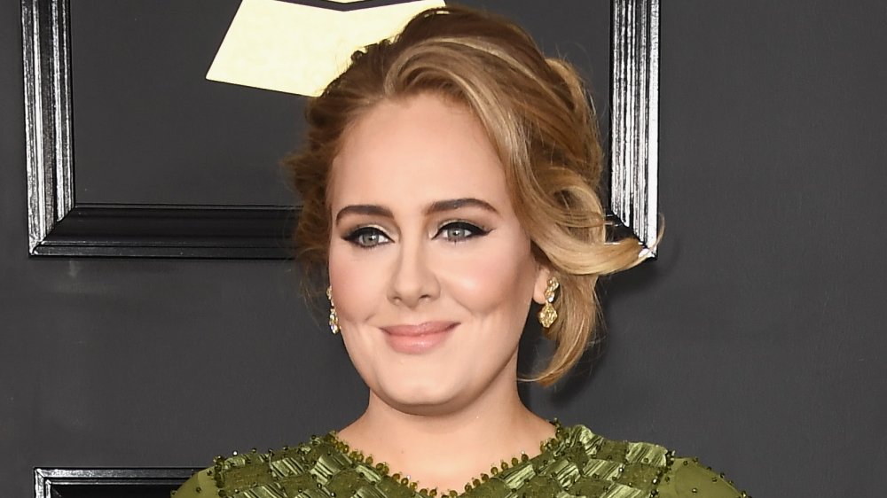 Adele smirking while posing at the Grammys