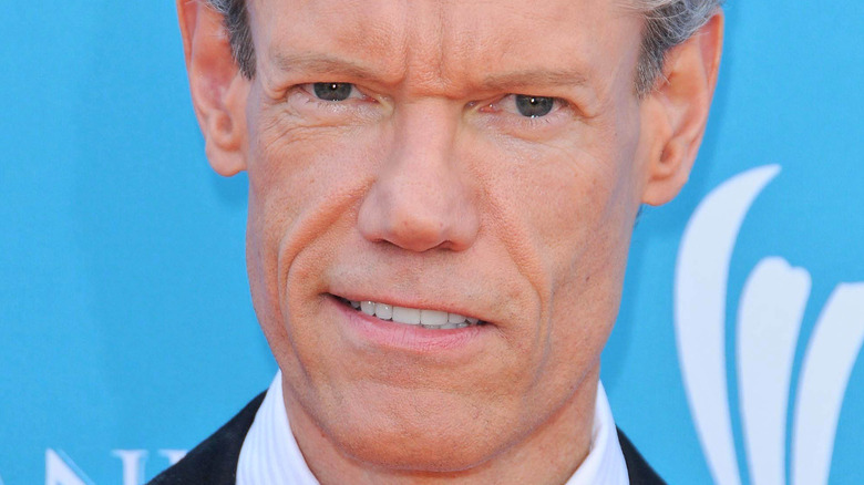 Randy Travis poses in a dark suit.