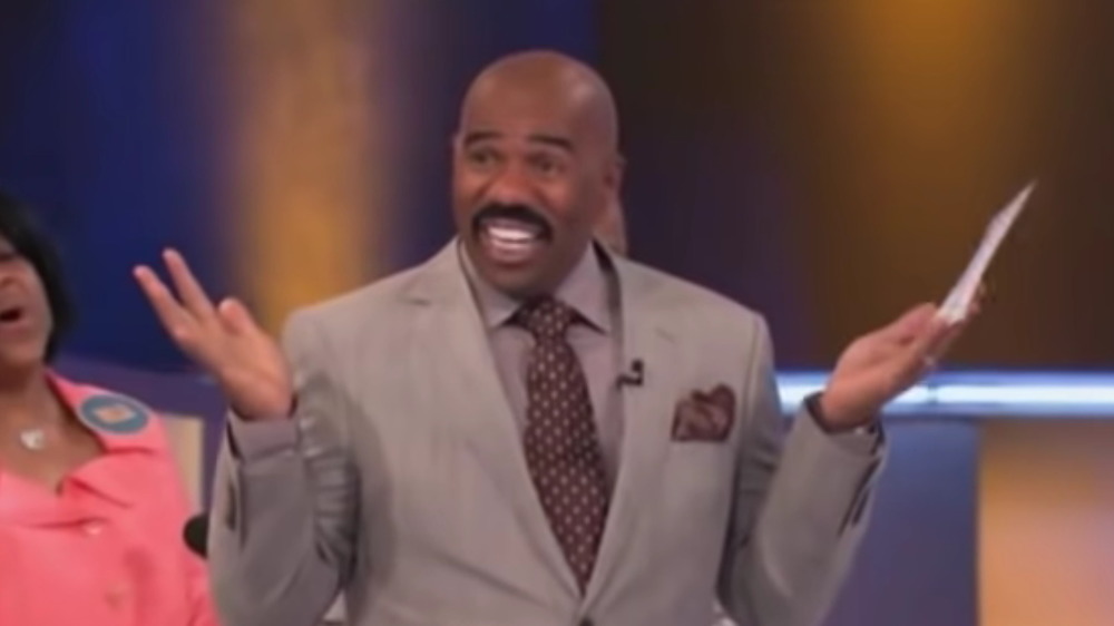 Steve Harvey holding his hands in the air on Family Fued