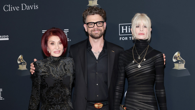 Sharon Osbourne posing with her adult children Jack and Kelly Osbourne in all-black outfits