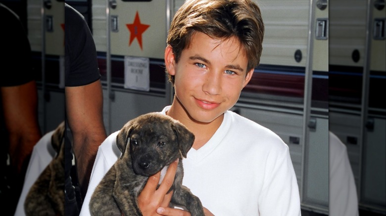Jonathan Taylor Thomas holding a dog.