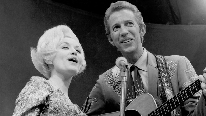 Dolly Parton and Porter Wagoner cheerfully belt out a tune.
