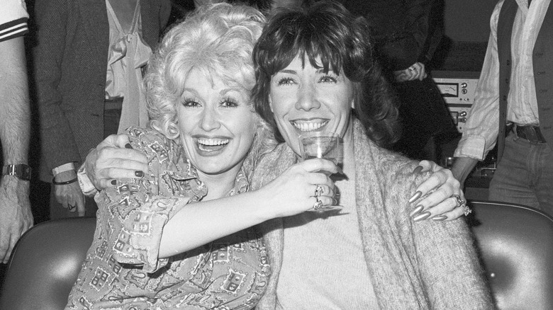 Dolly Parton and Lily Tomlin cheerfully raise a toast on set.