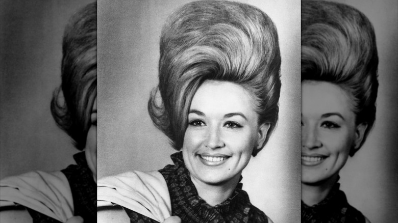 Dolly Parton, wearing voluminous, ski-high hair, smiles.