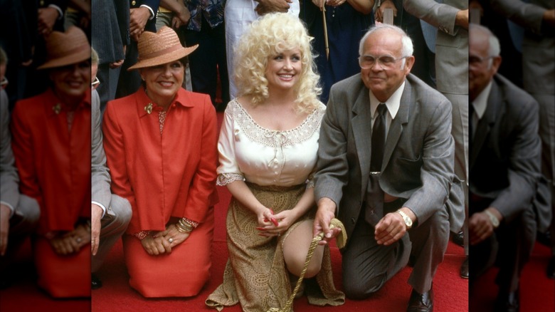 Dolly Parton smiles while kneeling beside her star in a group photo.