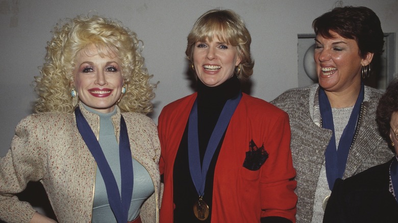 Dolly Parton smiles in a group photo with Sharon Gless and Tyne Daly.
