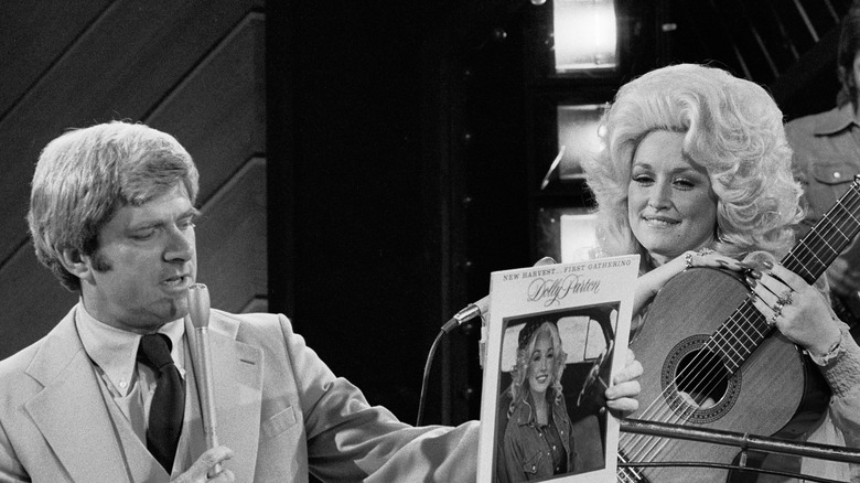 Phil Donahue holds up a copy of Dolly Parton's album as the singer watches.
