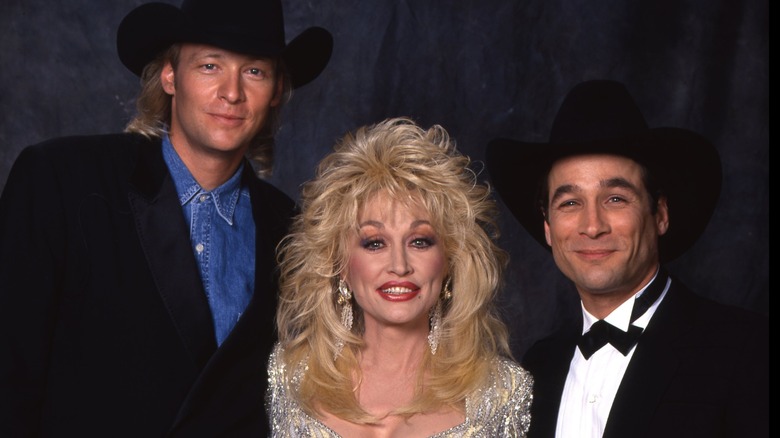 Dolly Parton, Alan Jackson, and Clint Black smile in a group photo.