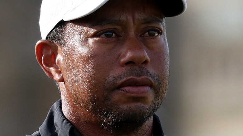 Tiger Woods, wearing a white baseball cap and looking serious