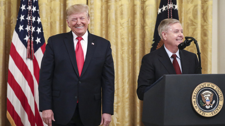 President Donald Trump looking on on as Sen. Lindsey Graham (R-SC) speaks during an event about judicial confirmations in the East Room of the White House
