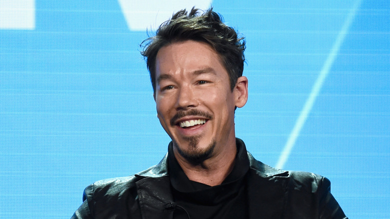 David Bromstad sitting in front of a blue HGTV background at a panel event.