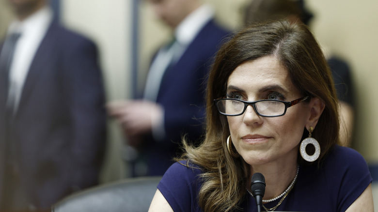 Nancy Mace leans toward a microphone with her eyeglasses sitting low on her nose.