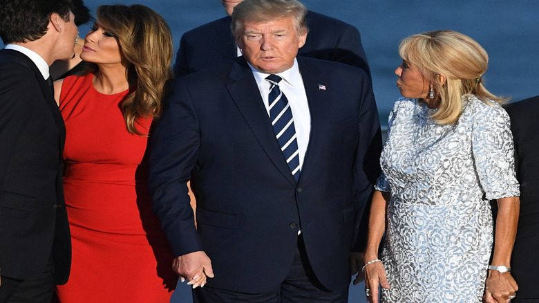 Melania Trump and Justin Trudeau greeting one another with a peck, Donald Trump to the side