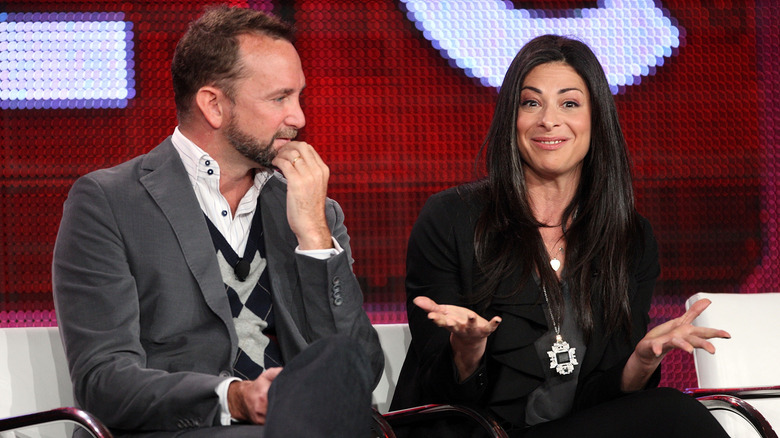 Clinton Kelly and Stacy London sitting on a couch talking.