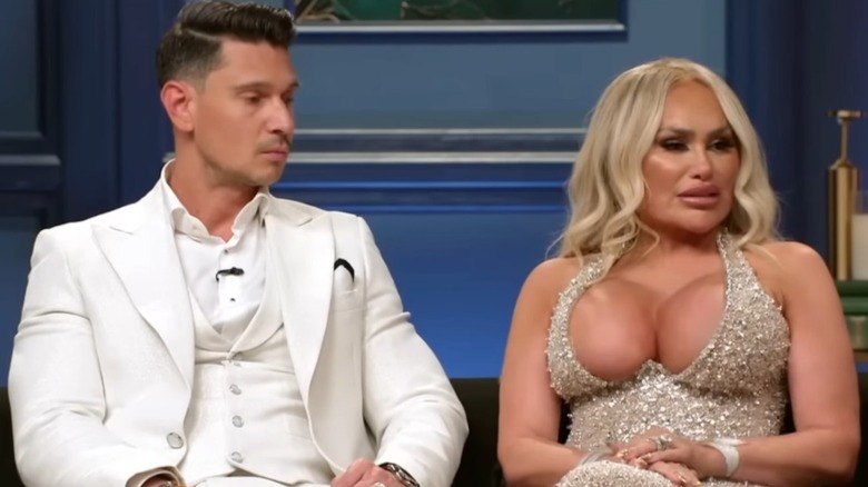 Darcey Silva, wearing a revealing sparkly dress, speaks while Georgi Rusev looks at her chest.