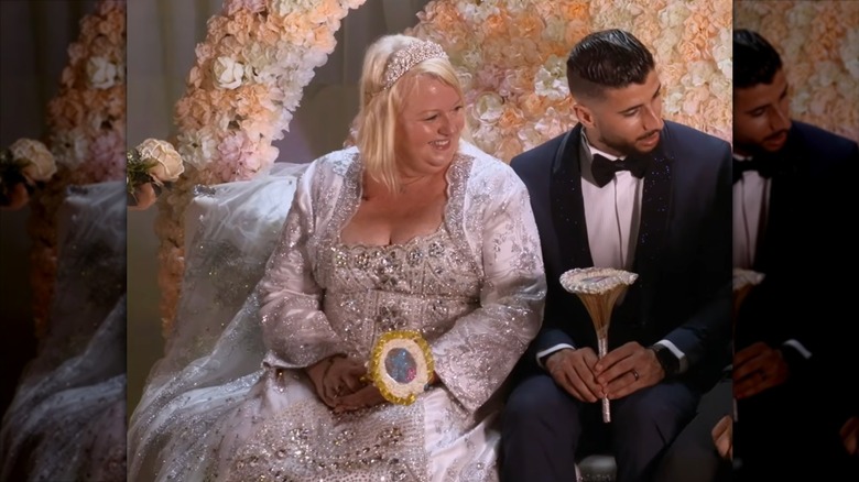 Laura Jallali smiles in her wedding gown as Aladin Jallali slips a ring onto her finger.