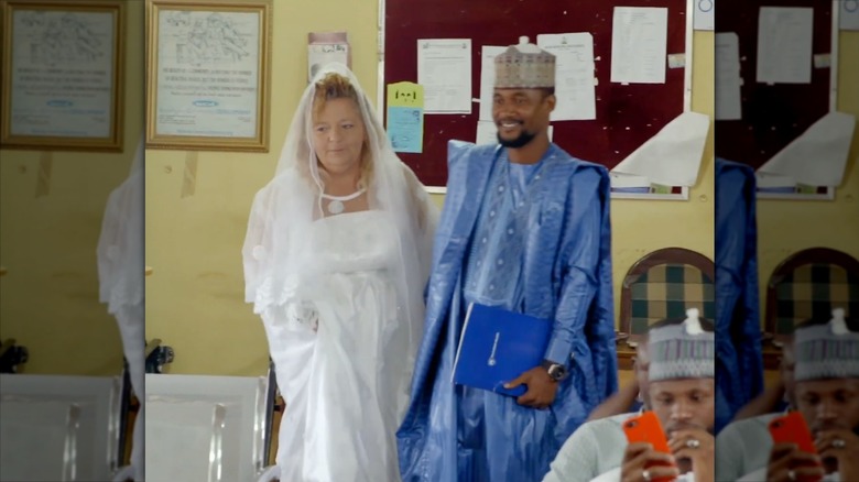 Lisa Hamme walks in her wedding gown with Usman Umar trailing close behind.