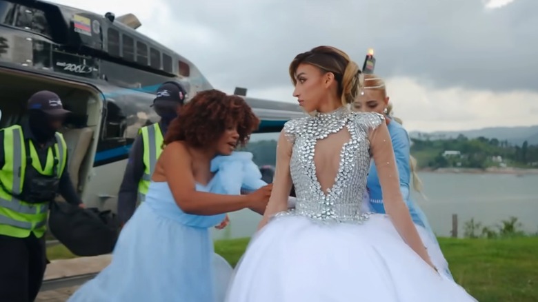 Madelein Perez looks to the side, as her bridesmaids adjust her wedding gown.