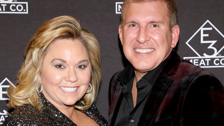 Todd and Julie Chrisley smile against black backdrop
