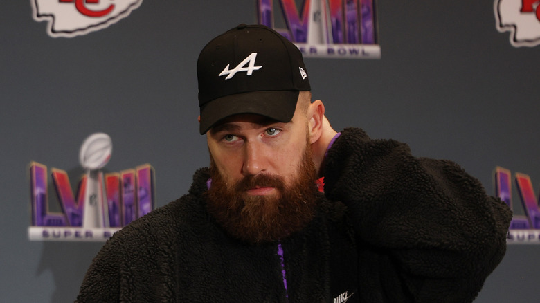 Travis Kelce looking serious in black fuzzy jacket