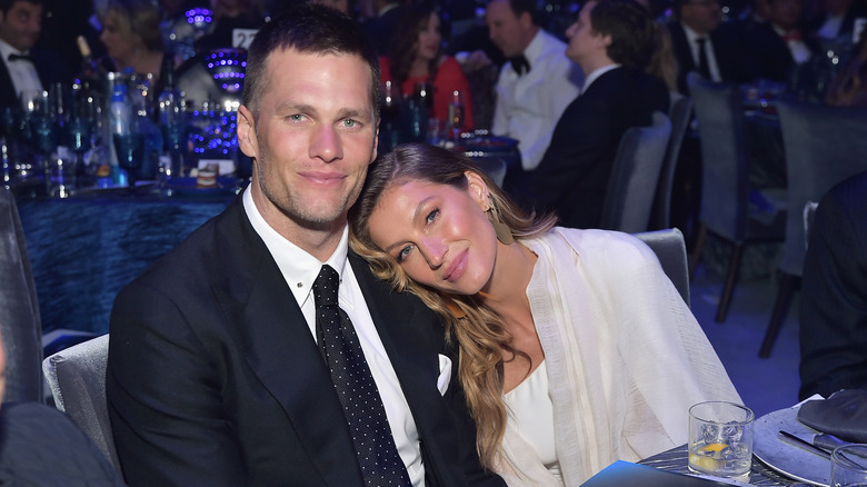 Gisele Bündchen laying her head on husband Tom Brady's shoulder as they sit and smile at an event