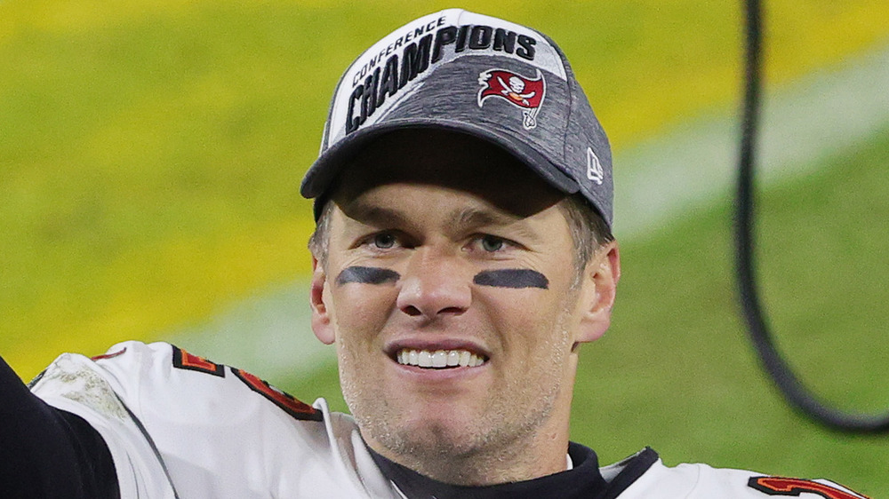 Tom Brady smiling on a football field