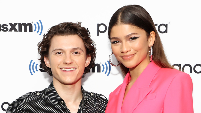 Tom Holland, Zendaya smiling together at an event