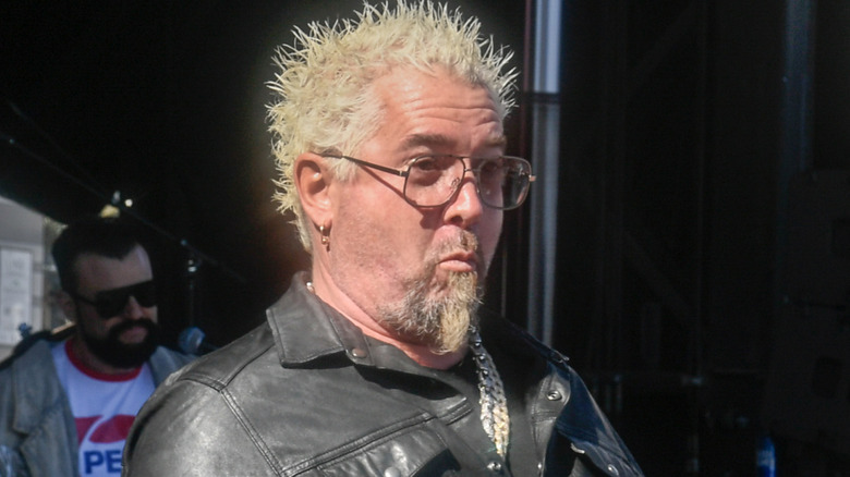 Guy Fieri posing for cameras outdoors while wearing leather