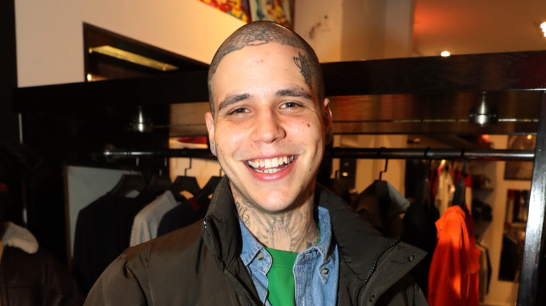 Richard Hilfiger smiling for cameras with a clothing rack behind him