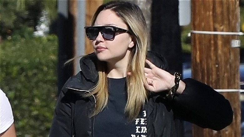 Amanda Bynes in sunglasses, tucking her hair back