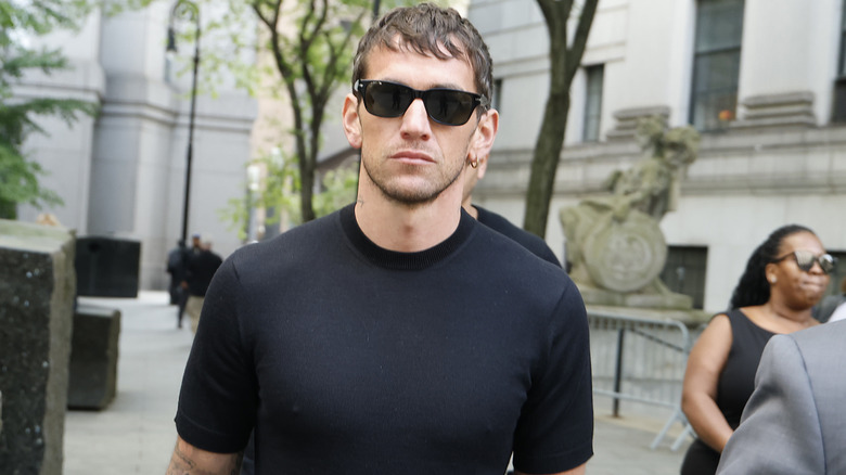 Alex Fine walking while wearing sunglasses and a black T-shirt
