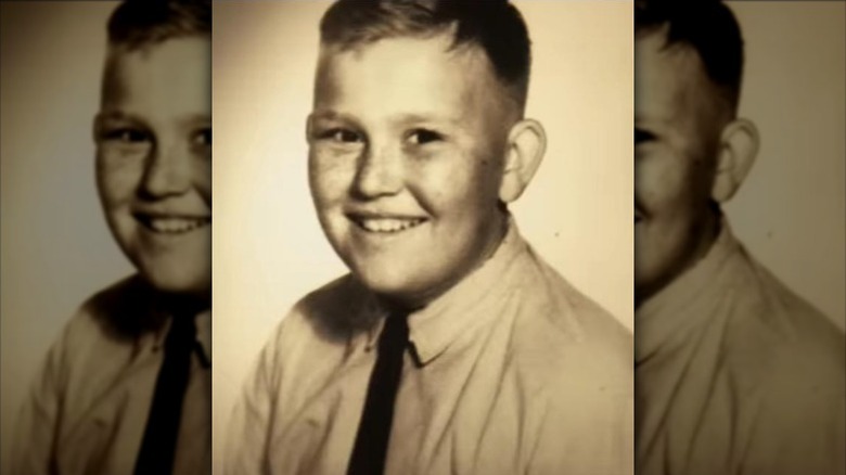 A young John Candy smiles in a shirt and tie