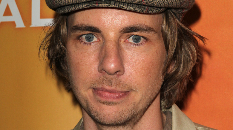 Dax Shepard with long hair and a newsboy cap, posing