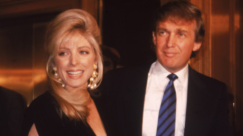 Marla Maples standing and smiling with Donald Trump in the 1990s