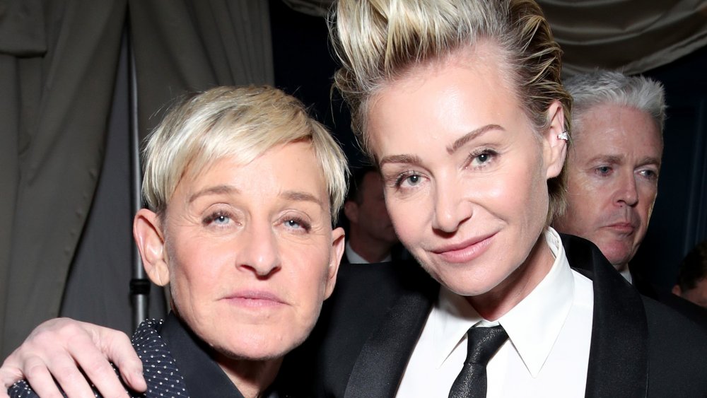 Ellen DeGeneres in a blue polka-dotted suit, Portia de Rossi in a black suit and tie, posing with their arms around each other