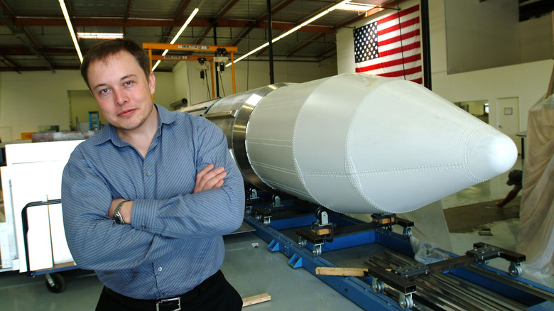 Elon Musk stands next to a rocket in 2004