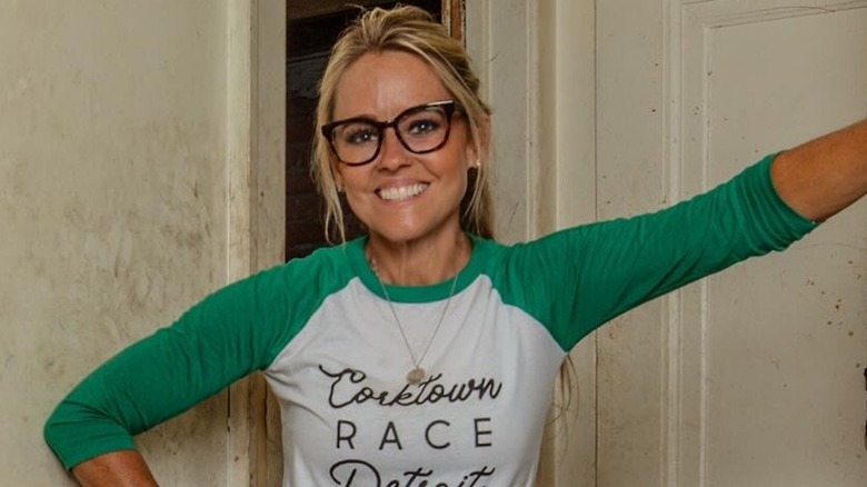 Nicole Curtis is all smiles, with one hand on her waist and the other holding a door.