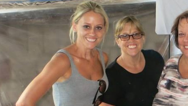 Wearing a checked shirt and pair of blue jeans, Nicole Curtis takes a mirror selfie.