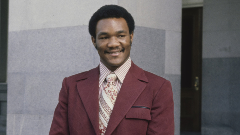 A young George Foreman smiling in a suit