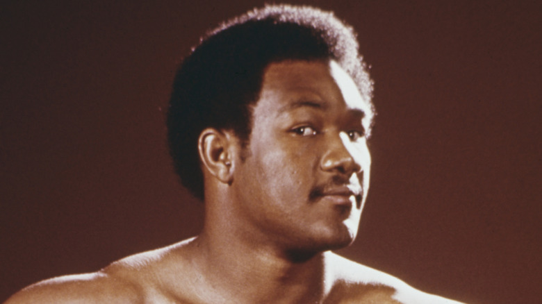 George Foreman posing for cameras in front of a brwon background