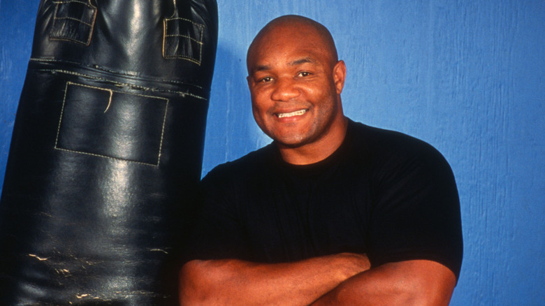 George Foreman posing for cameras near punching bag