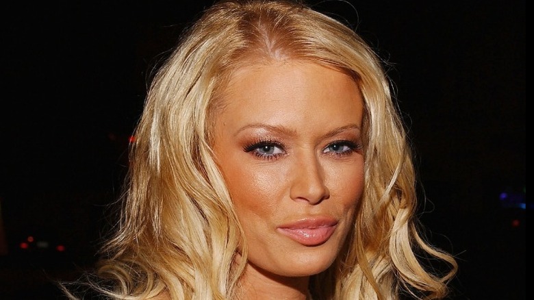 Jenna Jameson smirking with blonde hair in front of a dark background