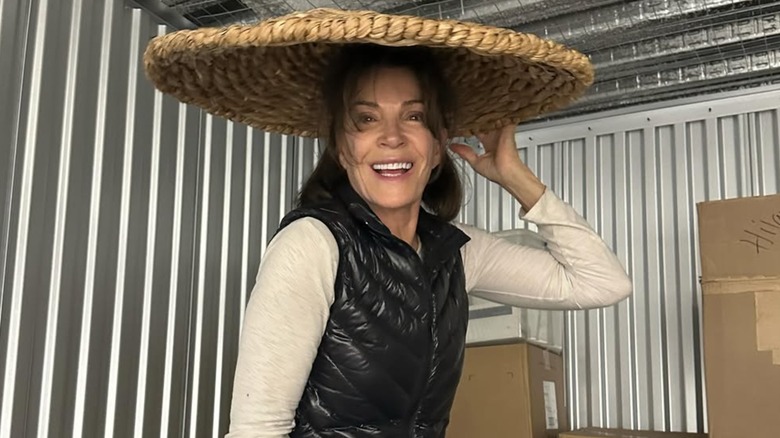 Hilary Farr smiling and holding a jute fruit bowl on her head